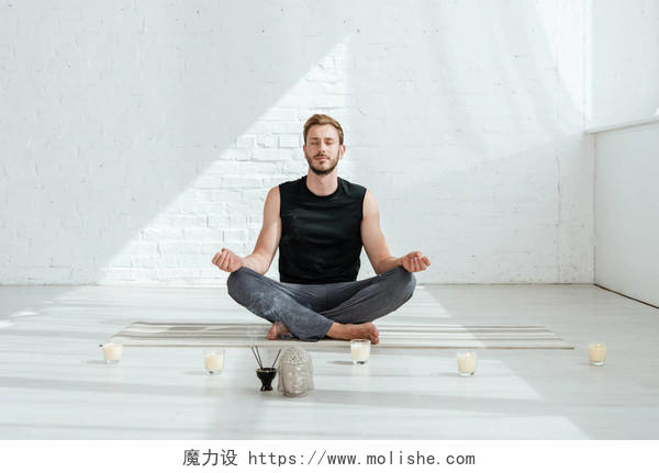 年轻英俊的男子在半荷花中练习瑜伽瑜伽打坐